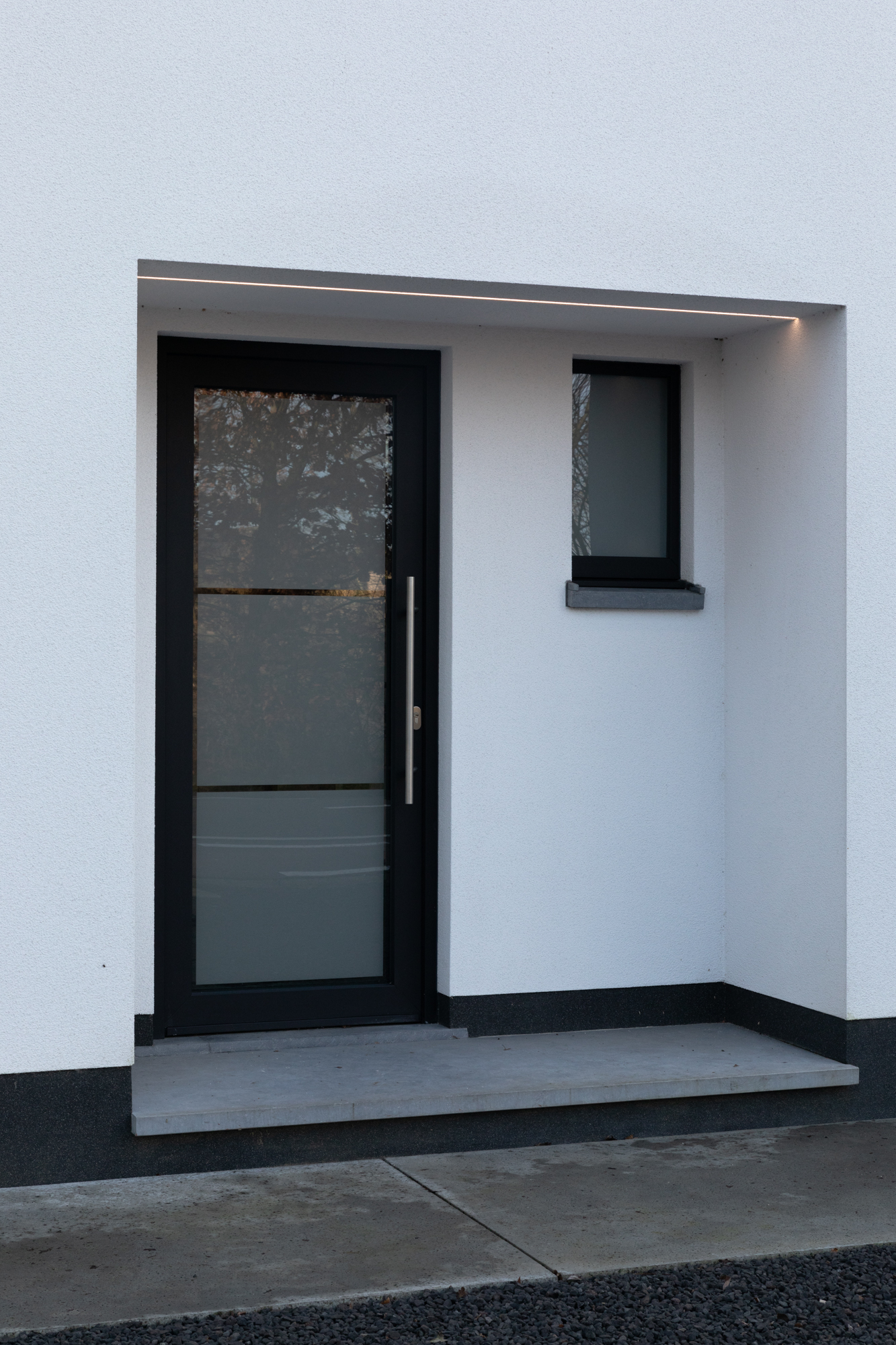Moderne donkere voordeur met glas in een witte gevel