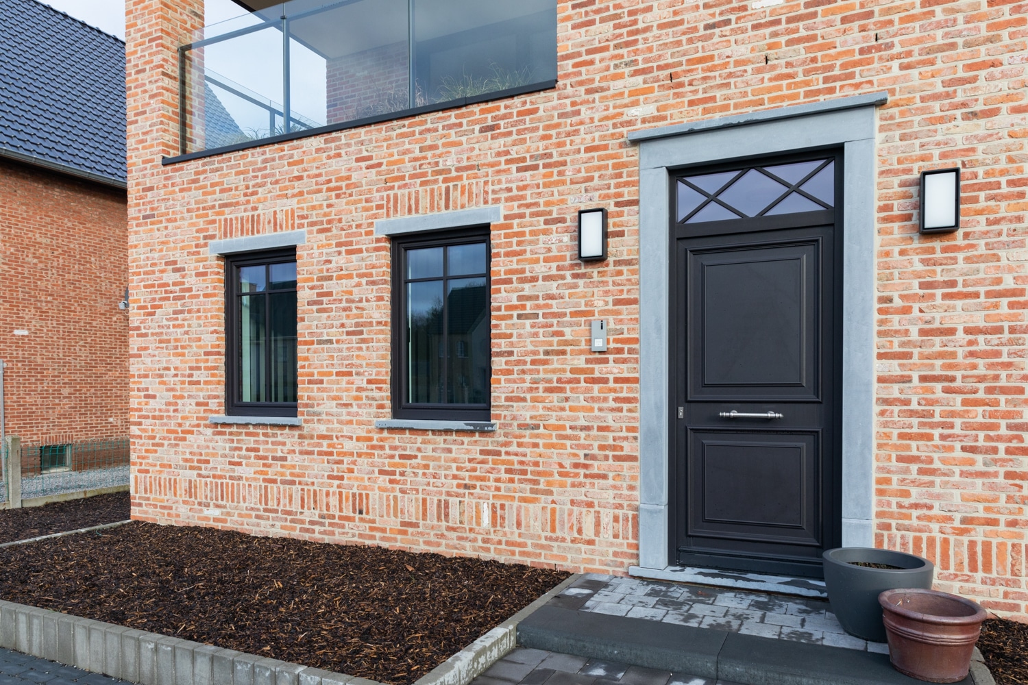 Donkere PVC voordeur in een bakstenen gevel
