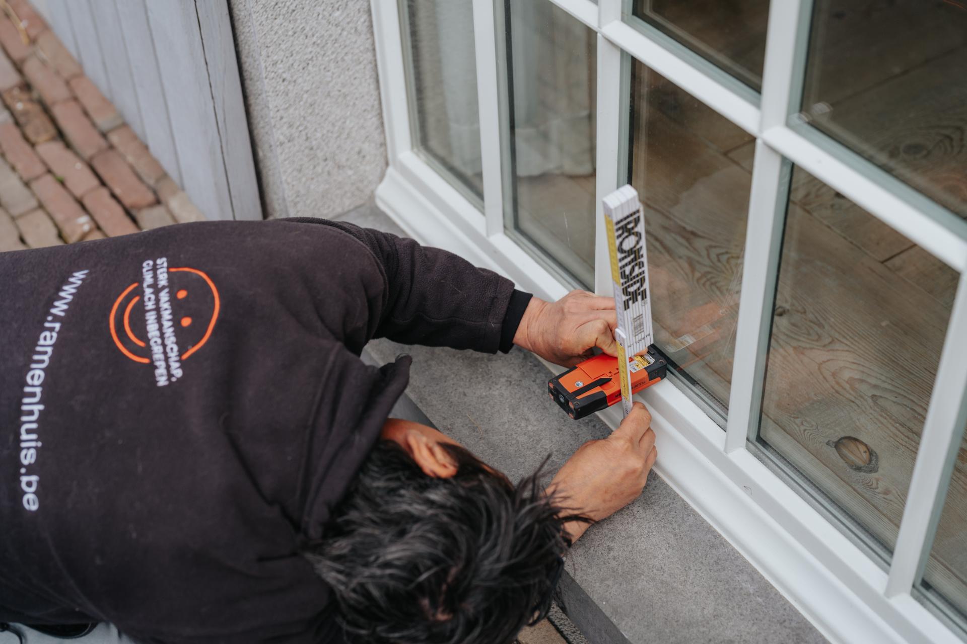 Technieker noteert afmetingen van ramen aan woning